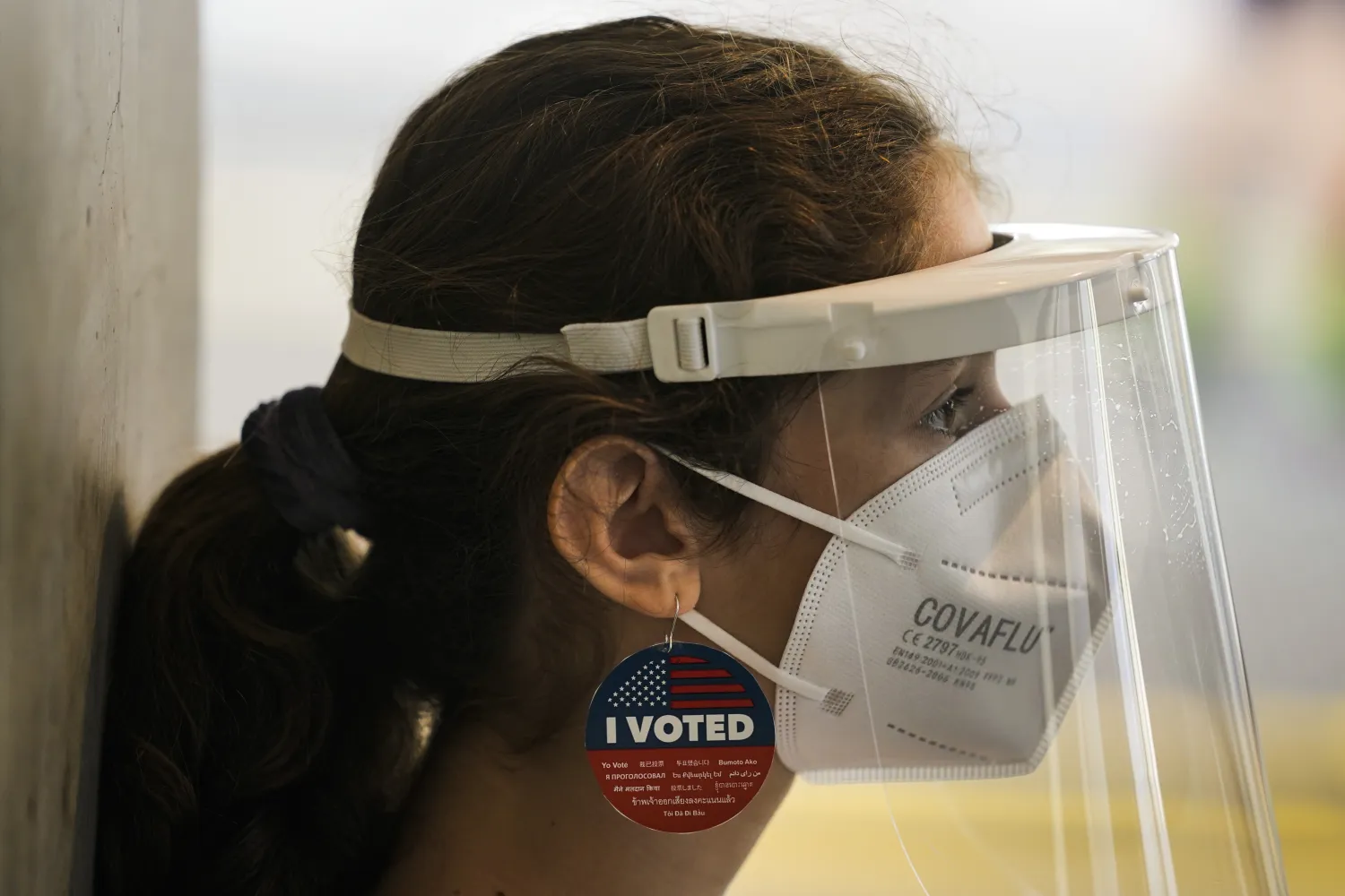 المتطوعة جوليا بيليغرينا ترتدي حلقاً من ملصق «لقد صوَّتُّ» وترتدي قناعاً واقياً أثناء عملها في مركز تصويت أقيم في لوس أنجليس (أ.ب)