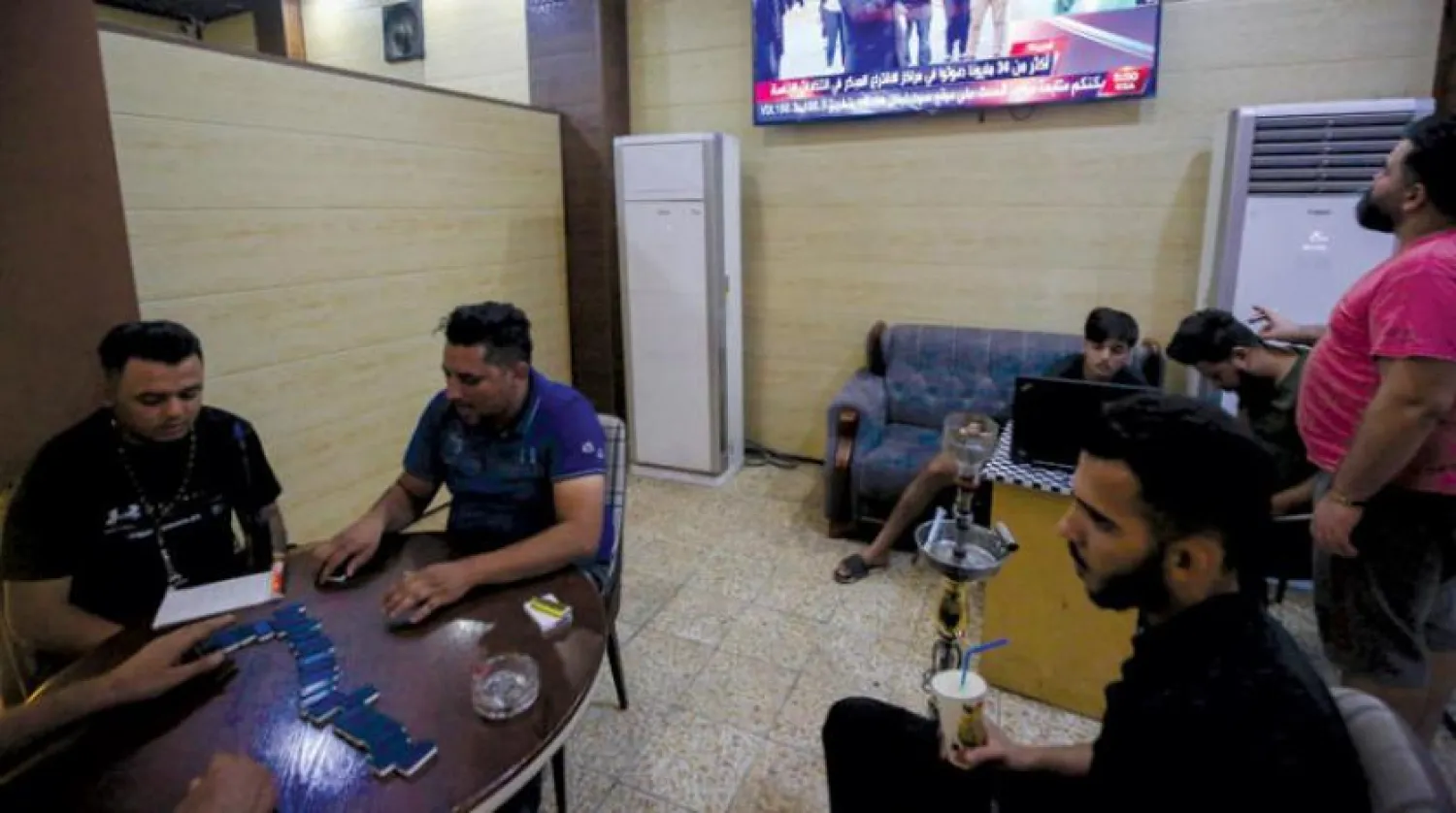 Bağdat’ta bir kafede görülen Iraklılar, televizyondan ABD seçimlerine dair haberleri takip ediyorlar (AFP)