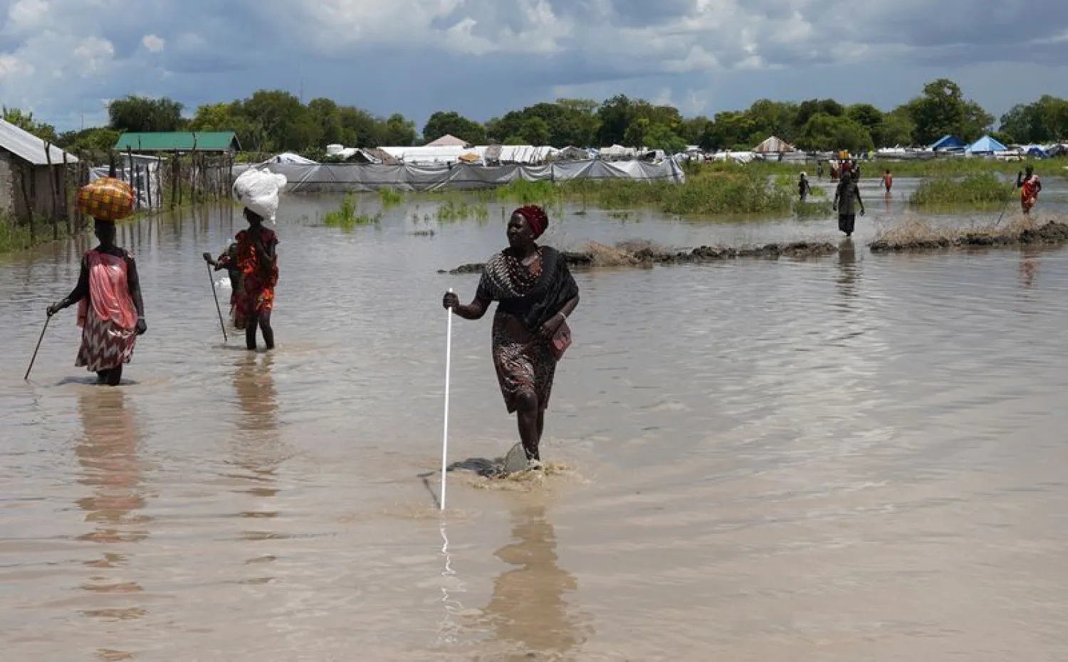 Women wade through flood waters after the River Nile broke the dykes in Pibor | AFP