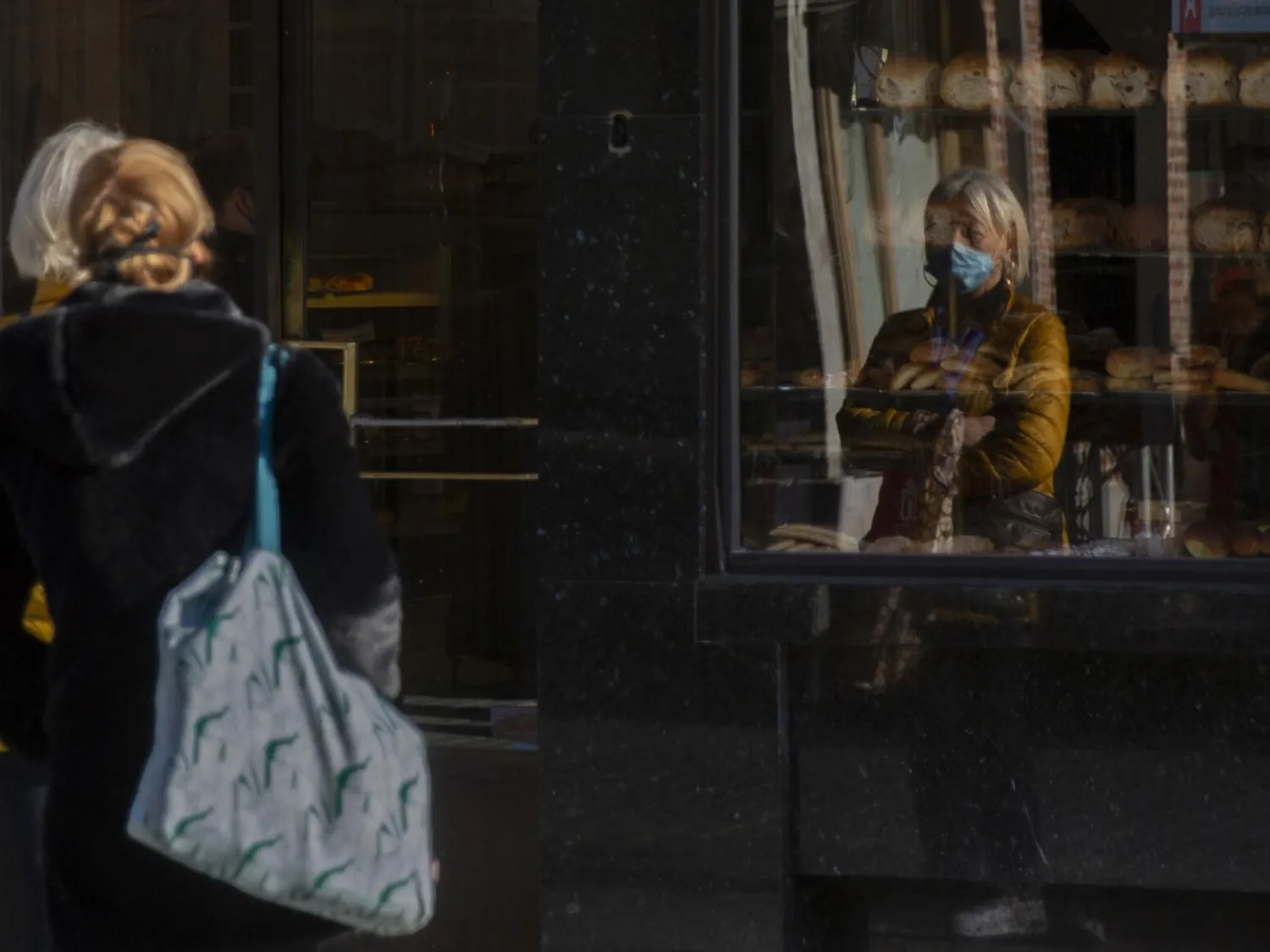 Two women wait in line at a bakery in Antwerp, Belgium, Wednesday, Nov. 4, 2020. Belgium, proportionally still the worst-hit nation in Europe when it comes to coronavirus cases, said Wednesday there increasing signs of that a turning point in the crisis was drawing close. The announcement came in the wake of increased measures over the past weeks with bar and restaurant closures capped by a partial lockdown starting last Monday, which further restricted close contacts and closing non-essential shops. (AP Photo/Virginia Mayo)