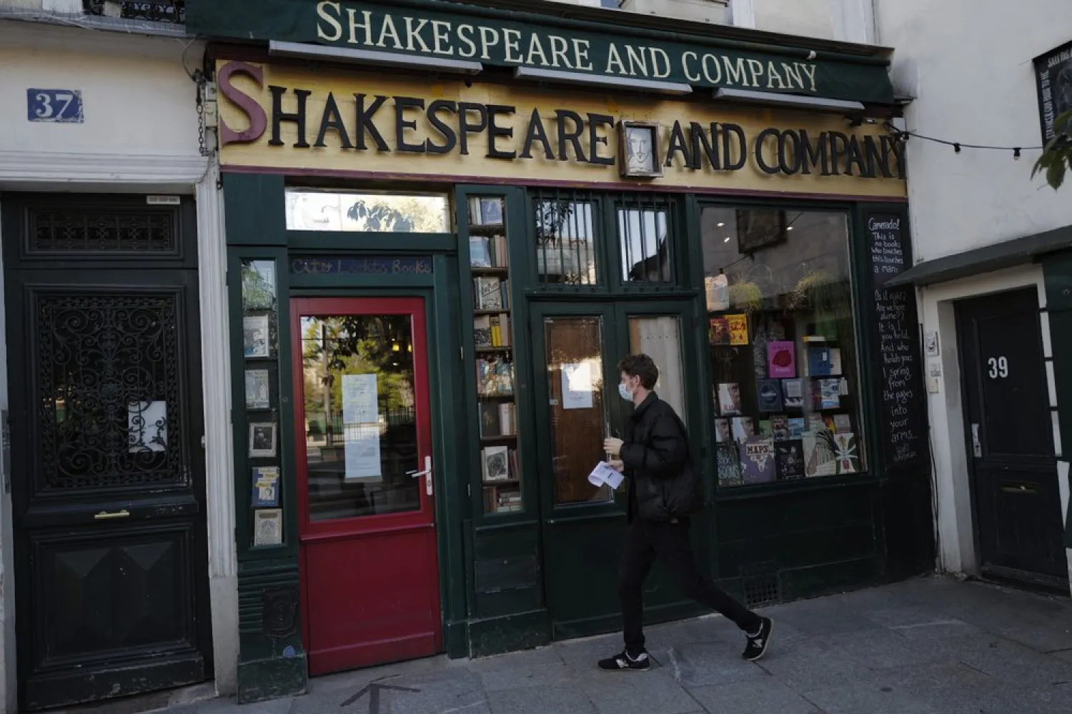 A man walks by the closed English and American literature Shakespeare and Co. bookstore in Paris, France, Thursday, Nov. 05, 2020. (AP Photo/Francois Mori)
