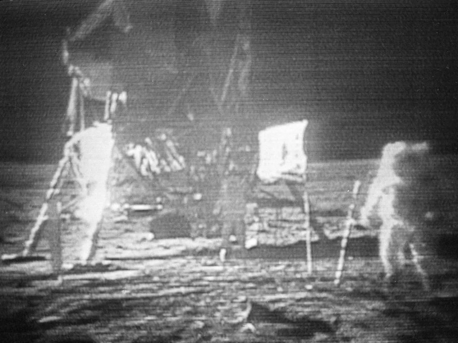 In this July 20, 1969 image made from television, Apollo 11 astronaut Neil Armstrong, right, trudges across the surface of the moon leaving behind footprints. The US flag, planted on the surface by the astronauts, can be seen between Armstrong and the lunar module. Edwin E. Aldrin is seen closer to the craft. (NASA via AP