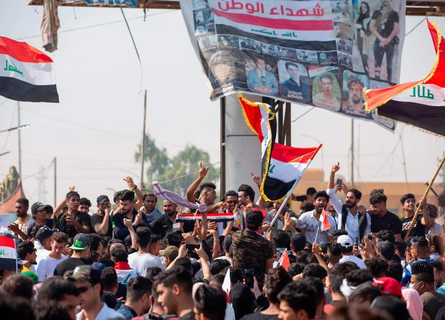 Iraqi demonstrators wave flags as they gather near the local administration building in the southern city of Basra. (AFP)