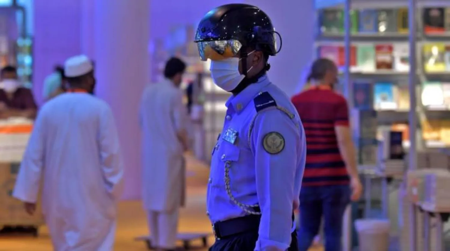 Bir Emirlik polisi, Şarika Uluslararası Kitap Fuarı'nda insanların ateşini kontrol etmek için maske ve kask takıyor (AFP)
