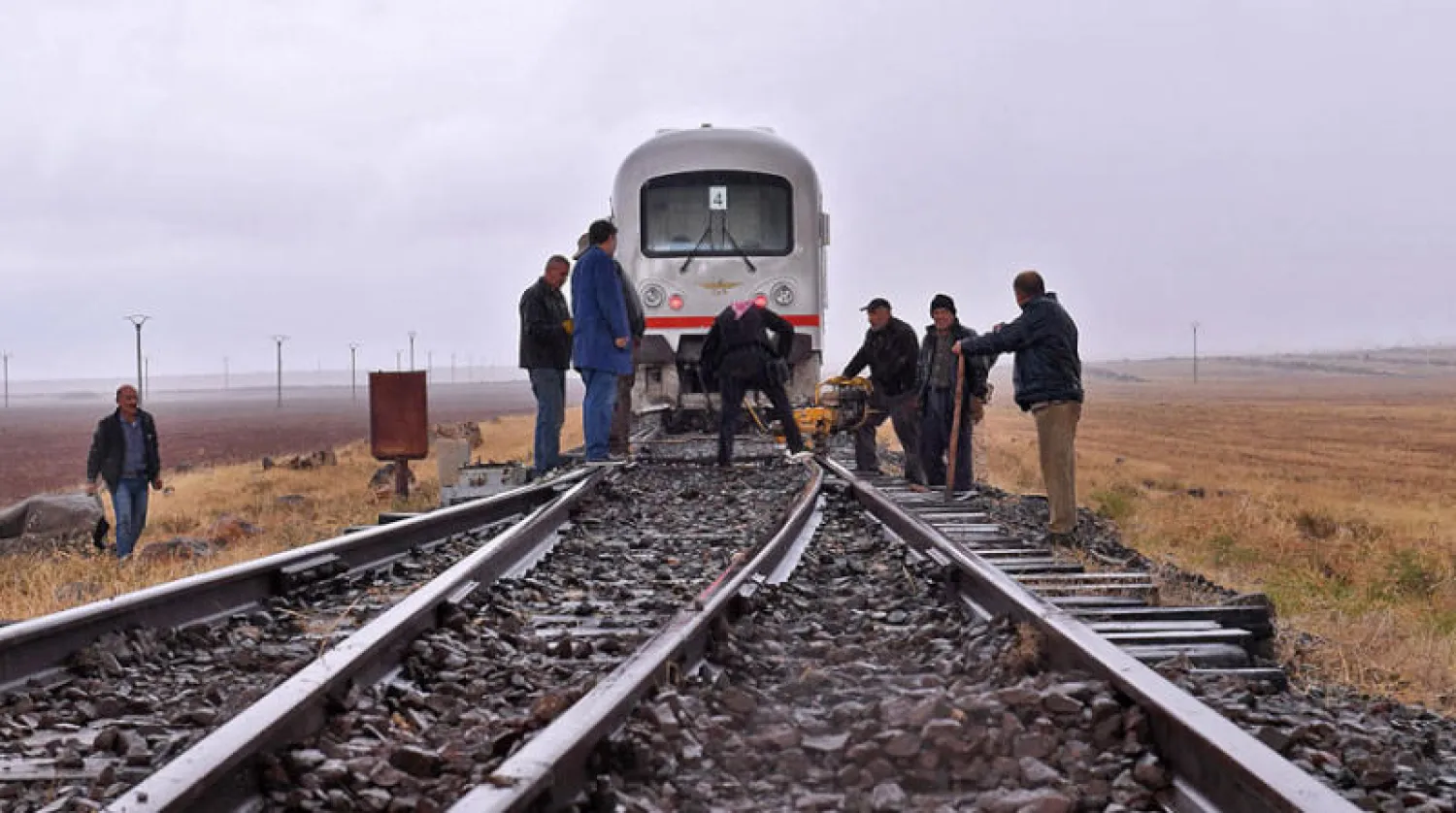 عمال يصلحون سكة القطار في شمال غربي سوريا (أ.ف.ب)