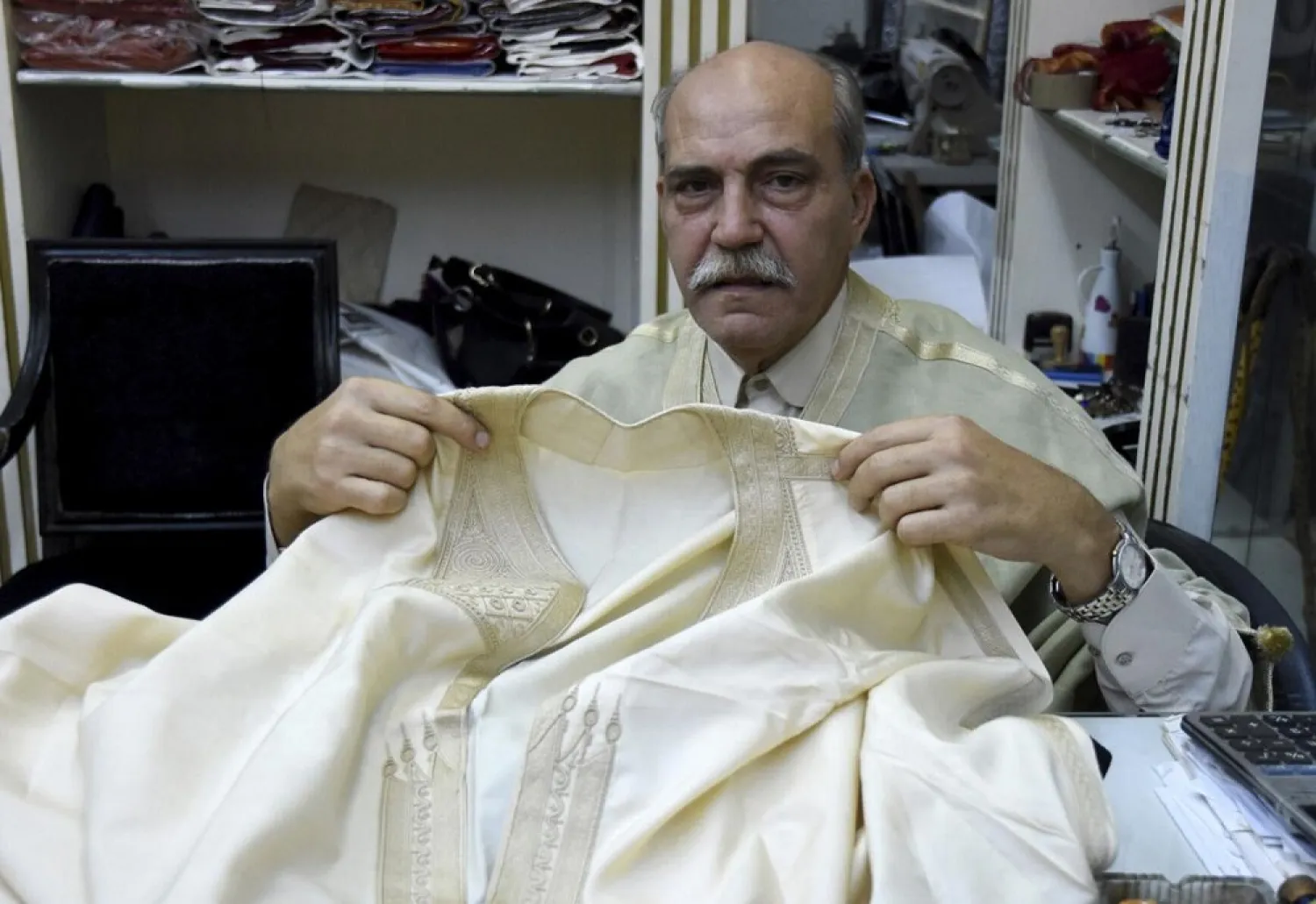 Lasaad El Beji Amine El Hrairia, a silk weaver In Tunis' Medina and that Hassan Ben Ayech, the designer for the Bardo Collection, holds a fabric in Tunis, Monday Oct.5, 2020. (AP)