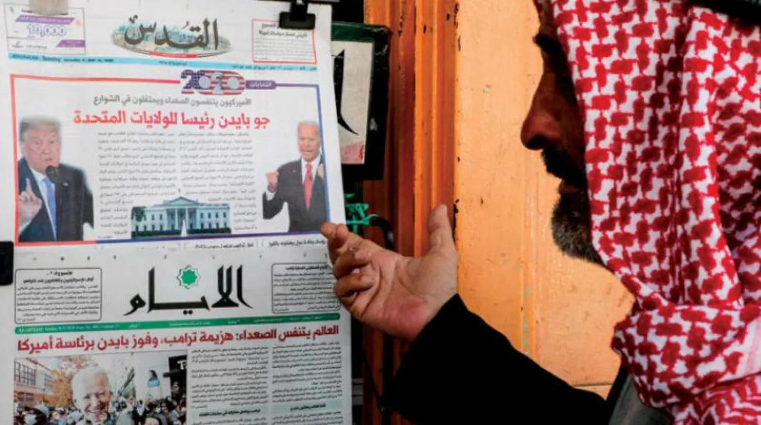 A man in Hebron standing in front of local Palestinian newspapers reporting Joe Biden’s victory in US presidential elections | AFP