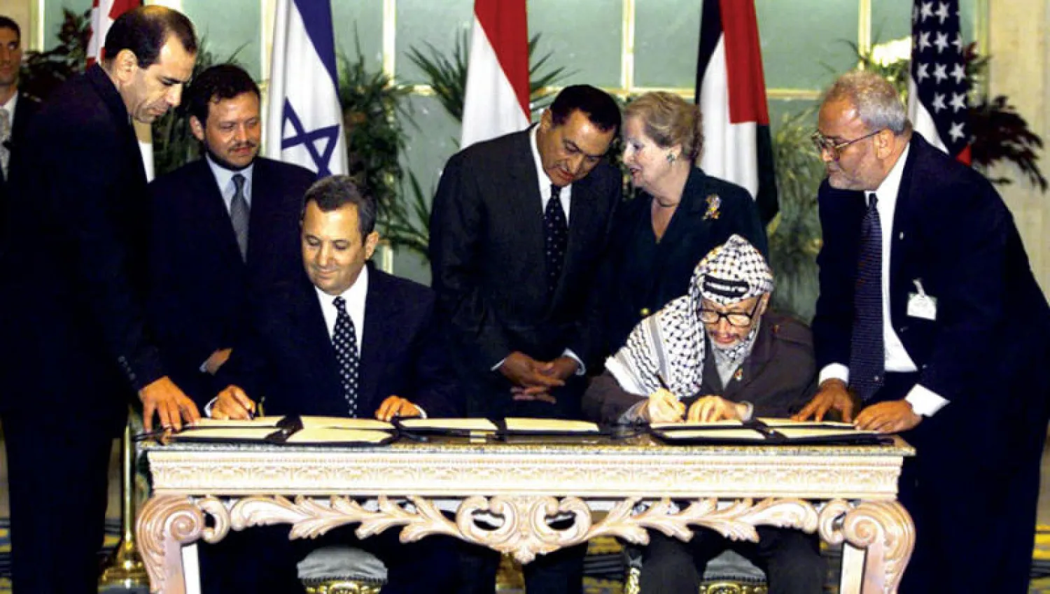 عريقات (يمين) إلى جانب الزعيم الفلسطيني الراحل ياسر عرفات أثناء توقيعه اتفاقية مع ايهود باراك في 1999.