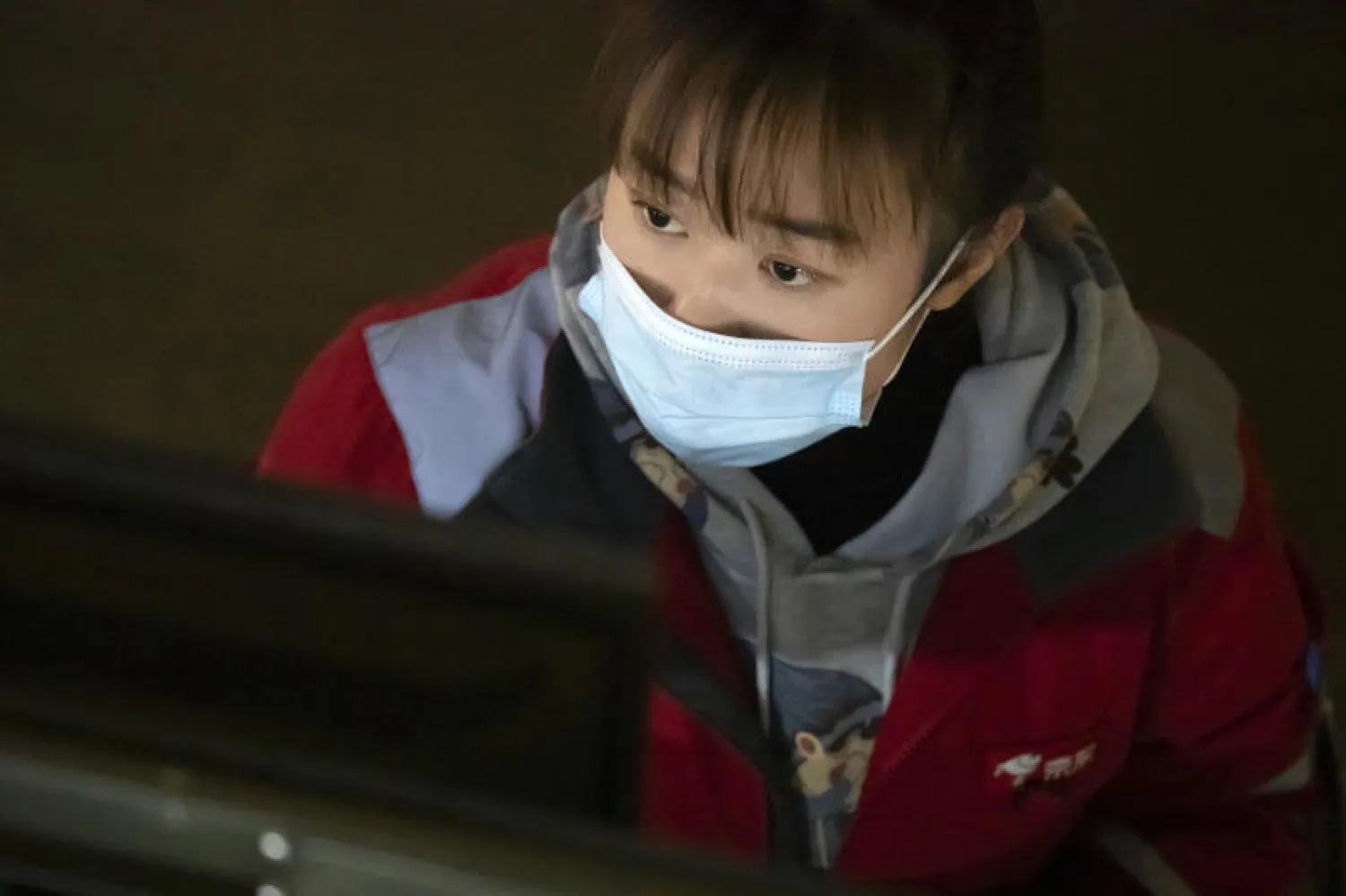 موظفة ترتدي كمامة للحماية من فيروس كورونا في إحدى الشركات بالصين (أ.ب)