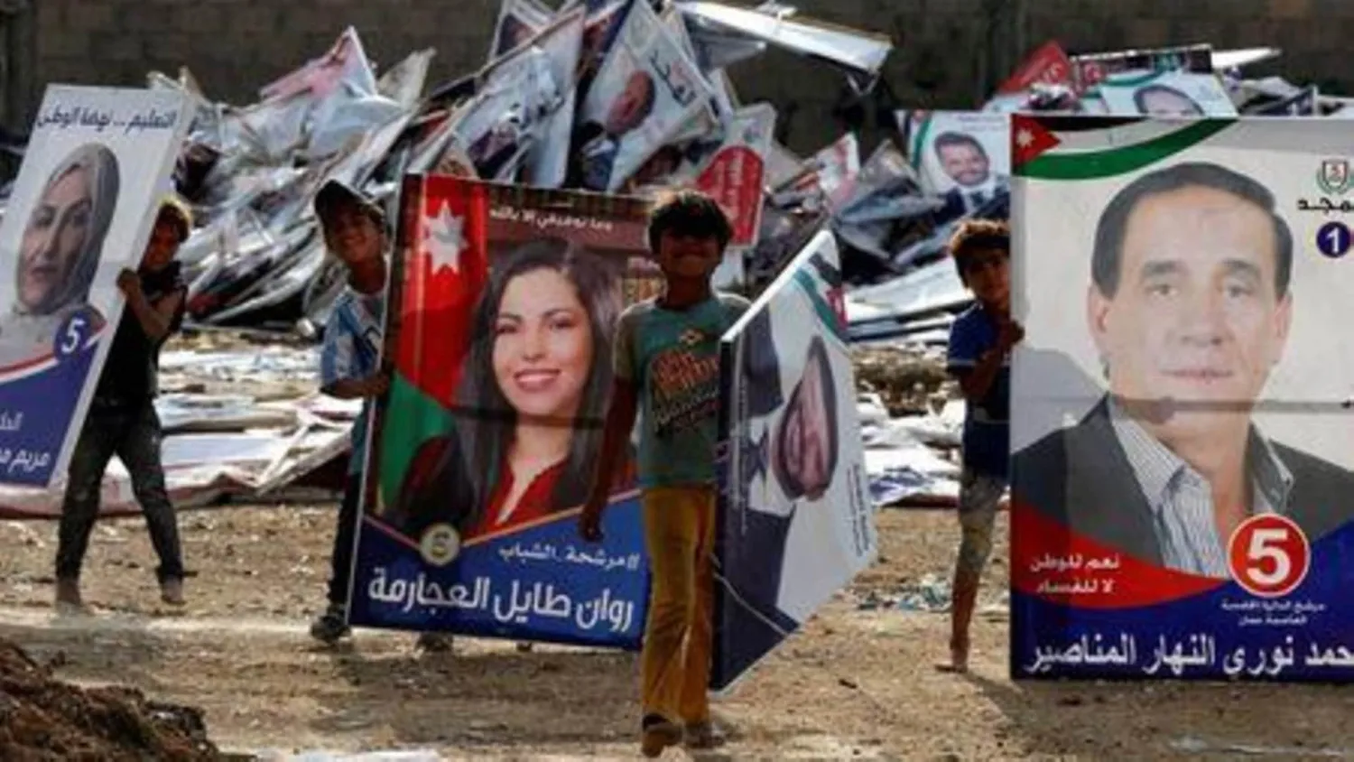 Children pose as they search for wood in parliamentary candidates' posters after elections results were announced in Amman, Jordan November 12, 2020. REUTERS/Muhammad Hamed
