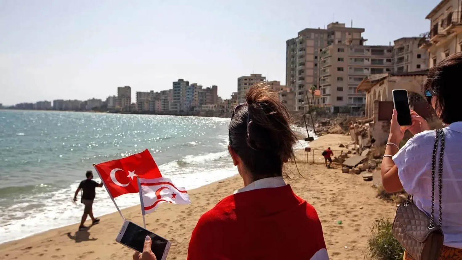 A woman holds the Turkish and the flag of the self-proclaimed Turkish Republic of Northern Cyprus as the public enters Varosha in the fenced-off area of Famagusta, on October 8. (AFP)