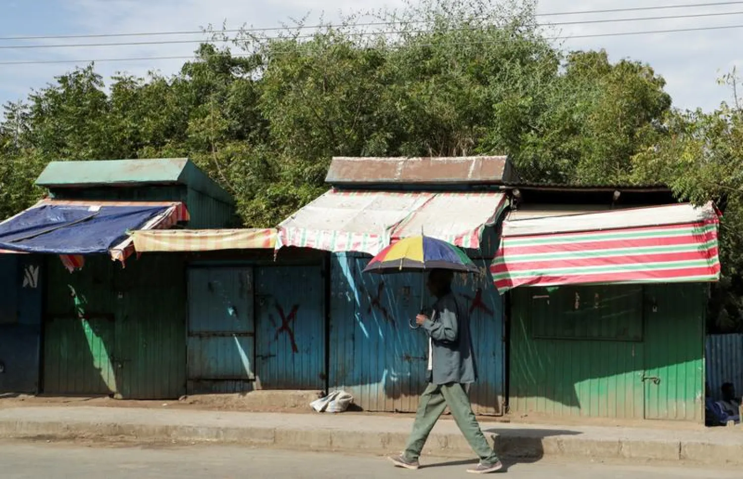 A man holds an umbrella as he walks past closed shops in Sanja, Amhara region near a border with Tigray, Ethiopia November 9, 2020. REUTERS/Tiksa Negeri