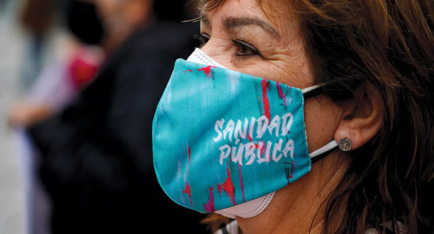 إسبانية في مدريد تضع كمامة كتب عليها «الرعاية الصحية العامة» (رويترز)