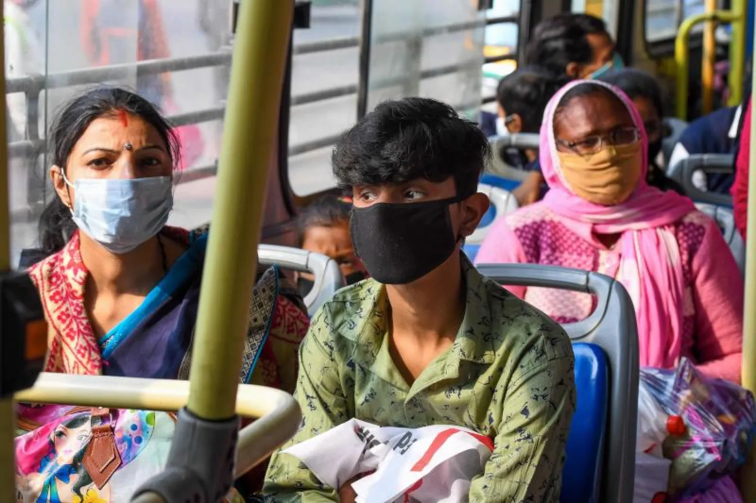 ركاب حافلة في نيودلهي يرتدون كمامات (أ.ف.ب)