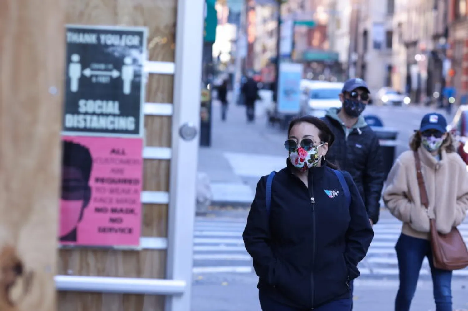 مارة يرتدون أقنعة الوجه الواقية للحماية من كورونا بشارع في نيويورك (رويترز)