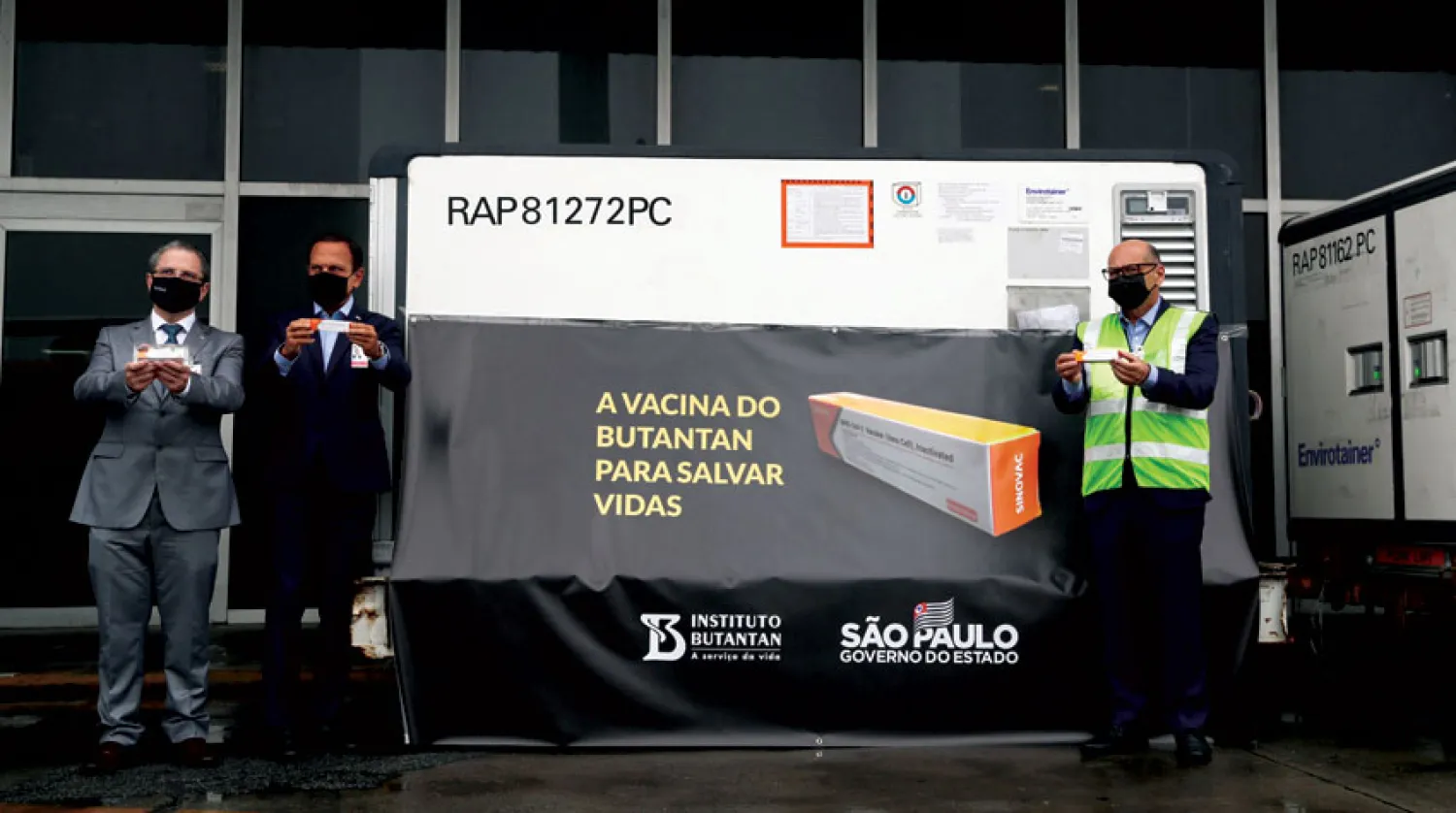 مسؤولون برازيليون يحملون جرعات من اللقاح الصيني (رويترز)