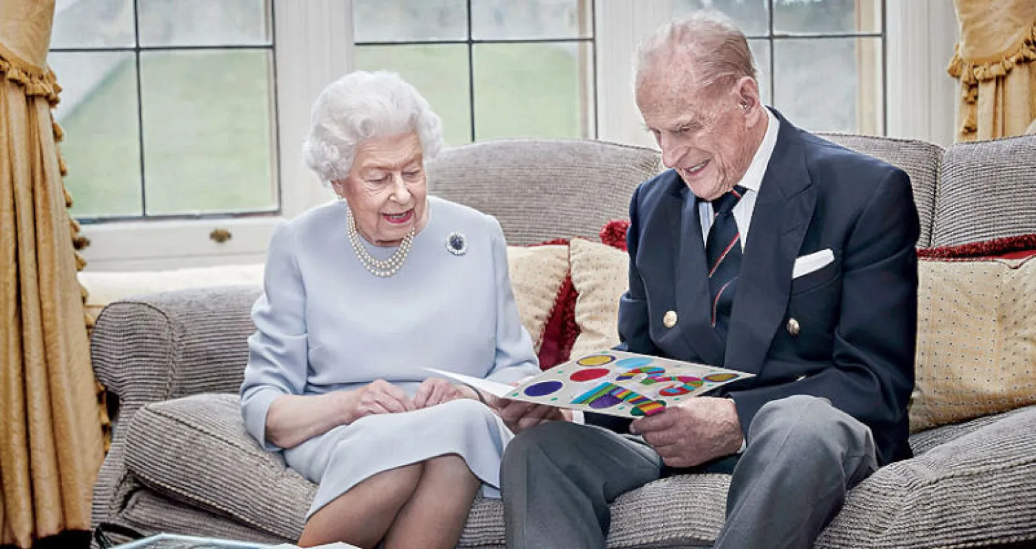 الملكة وزوجها ينظران إلى بطاقة تهنئة (أ.ب)