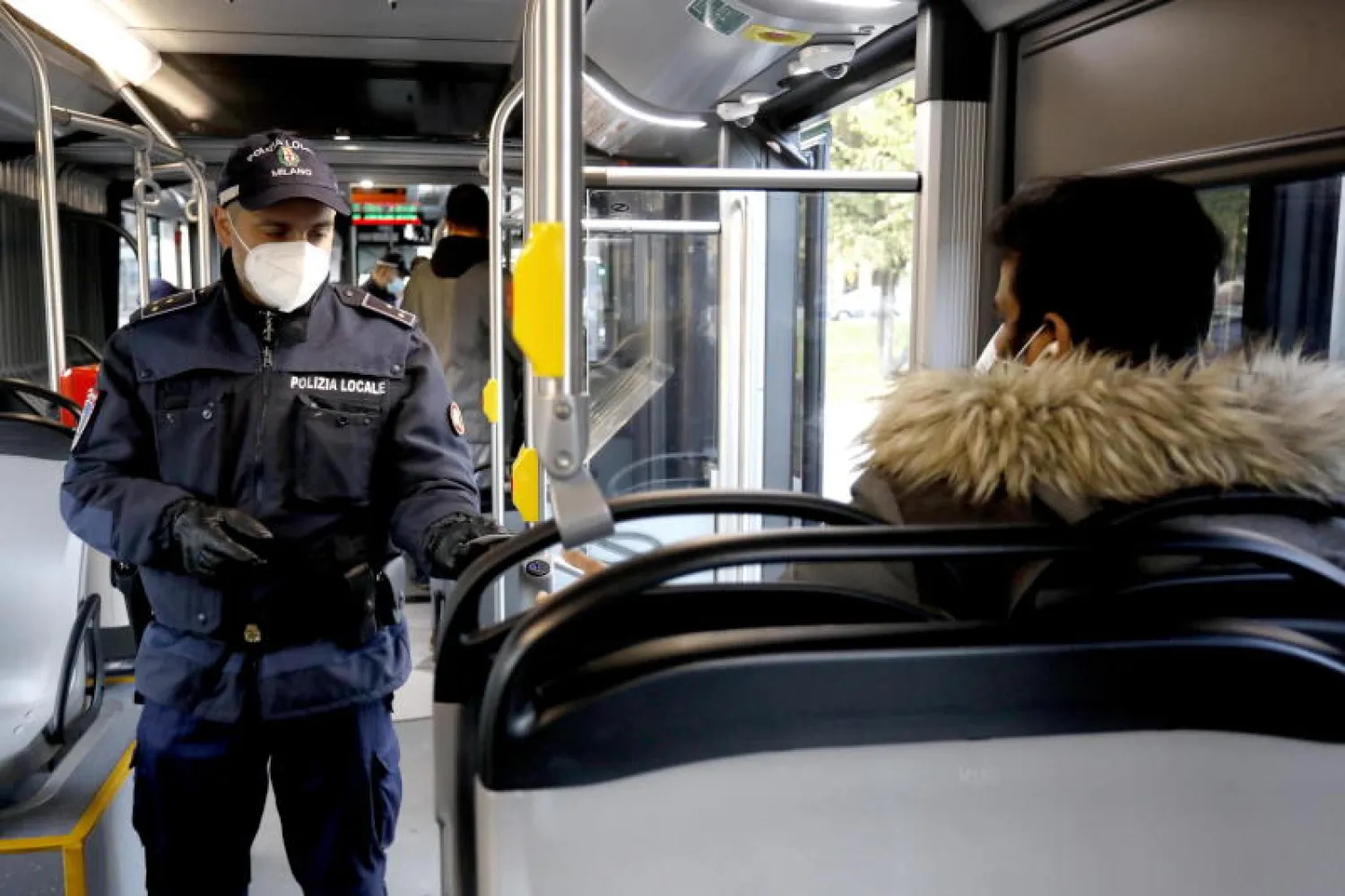 شرطي إيطالي يقوم بعملية تفتيش على حافلة وسط طوارئ بسبب جائحة كورونا في مدينة ميلانو (إ.ب.أ)