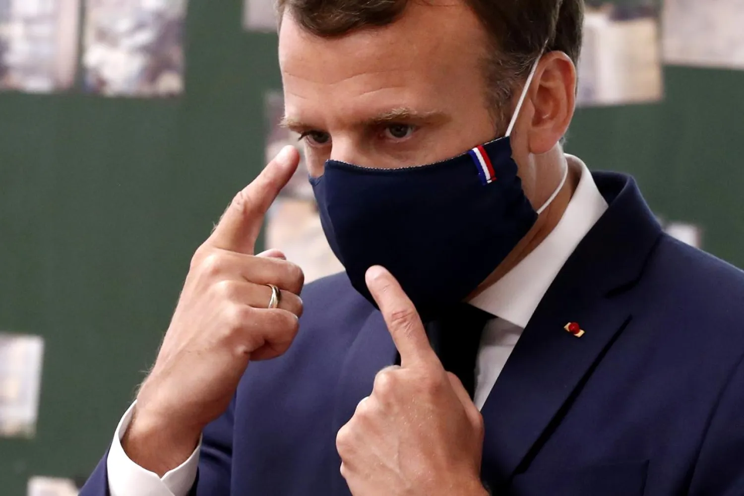 FILE PHOTO: France's President Emmanuel Macron wears a protective face mask with a blue-white-red colored ribbon as he gestures while speaking in Poissy, France, May 5, 2020. Ian Langsdon/Pool via REUTERS/File Photo