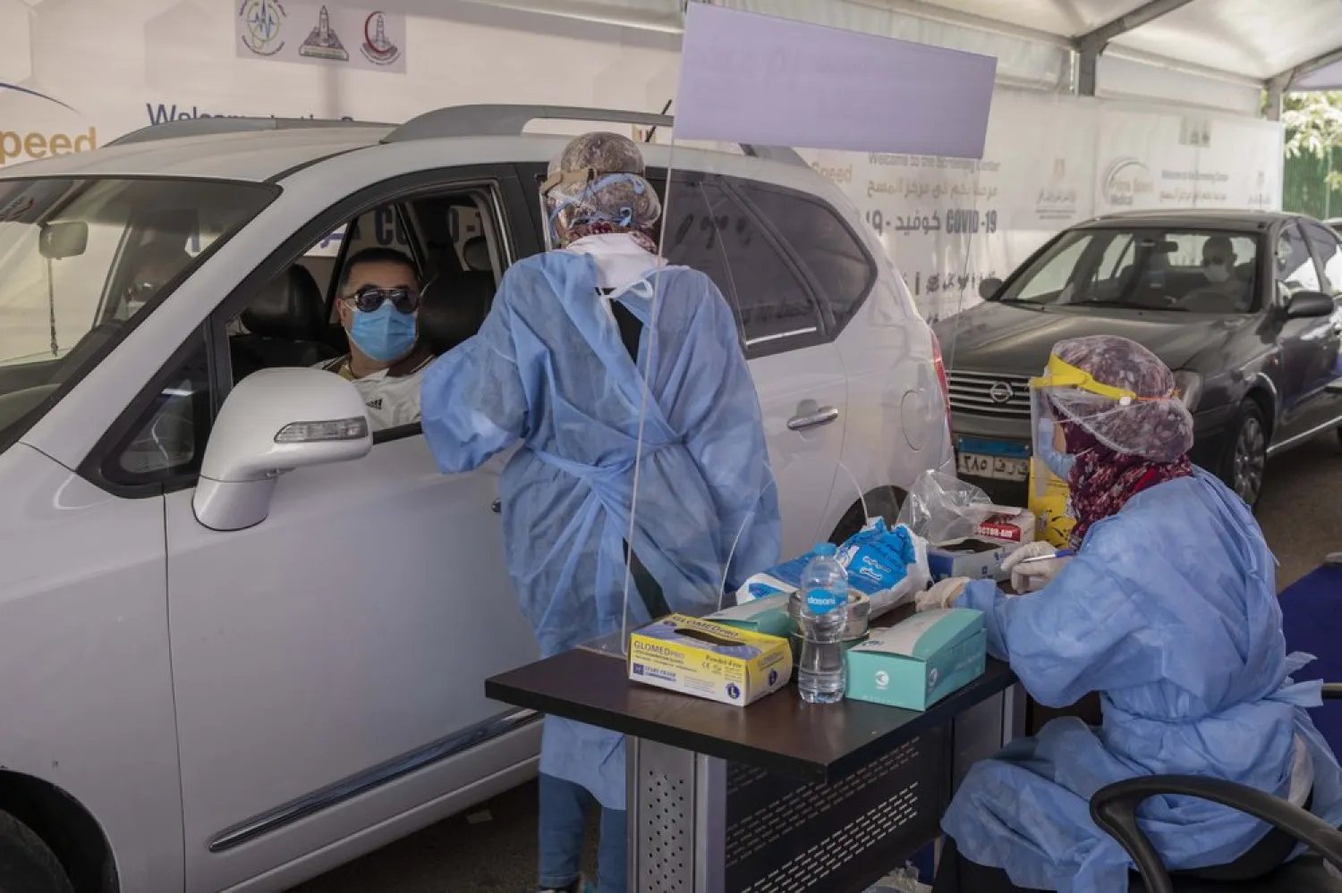 A health worker wearing protective gear prepares to take swab samples from people queuing in their cars to test for the coronavirus at a drive-through COVID-19 screening center at Ain Shams University in Cairo, Egypt, Wednesday, June 17, 2020. (AP Photo/Nariman El-Mofty)
