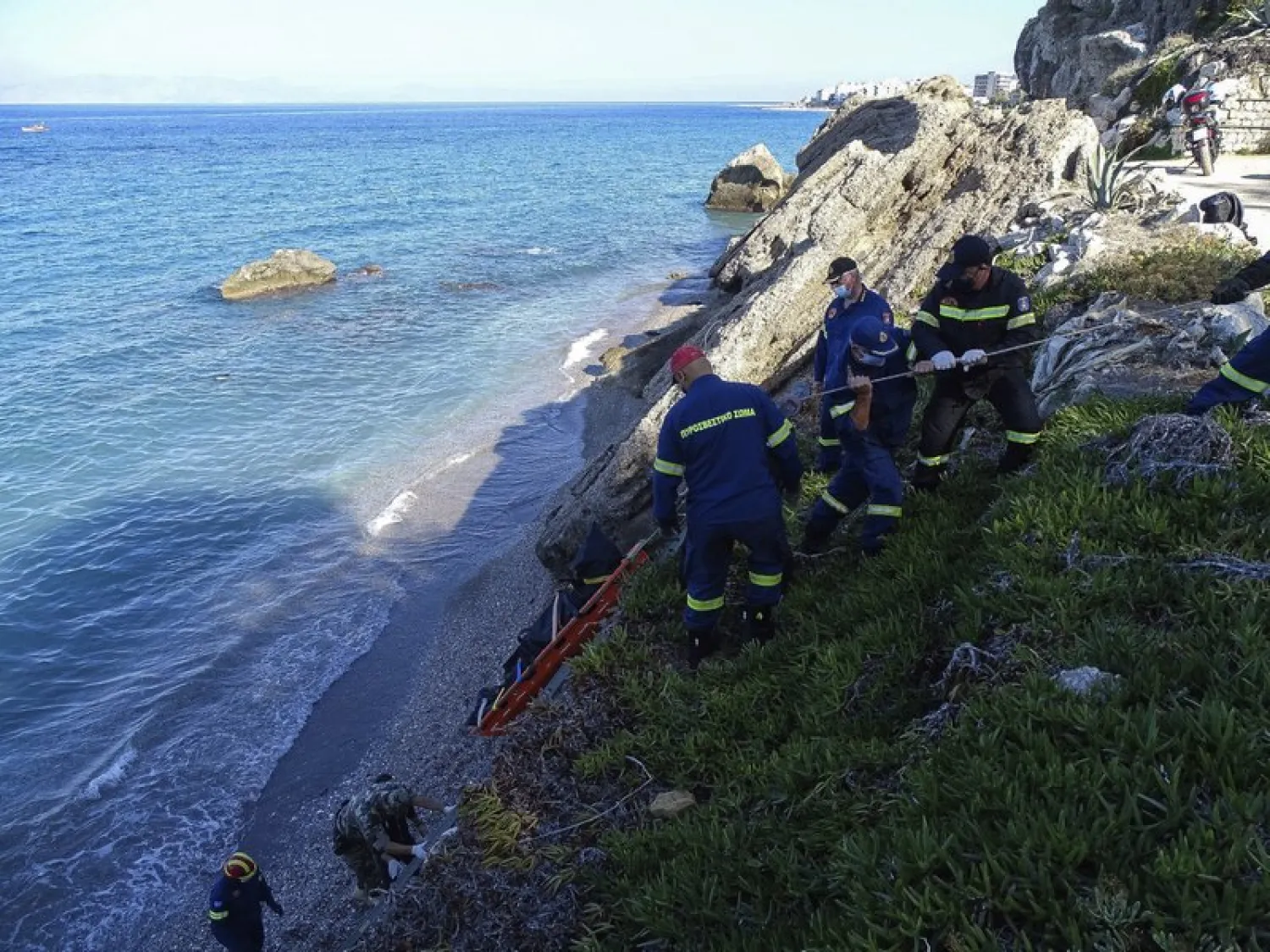 Firefighters retrieve the body of a migrant from the beach after a shipwreck on the island of Rhodes, southeastern Greece, Monday, Nov. 23, 2020. Greece's coast guard says a speedboat that appeared to have been smuggling migrants to the island of Rhodes from nearby Turkey partially sank before reaching land Monday, leaving one person dead. (Argyris Mantikos/Eurokinissi via AP)

