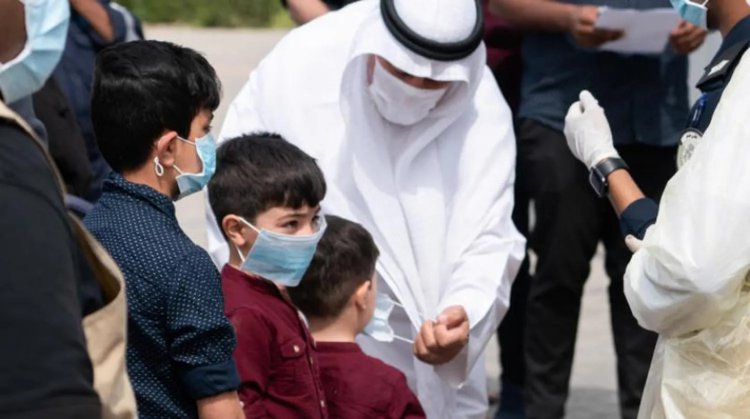 Kuveyt şehrinde bir baba test merkezine girmeden çocuğuna maske takıyor (Reuters)