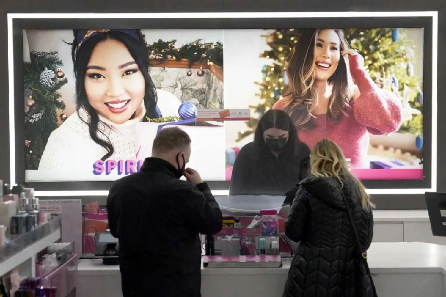 Cashier Druhan Parker, center, works behind a plexiglass shield Thursday, Nov. 19, 2020, as he checks out shoppers at an Ulta beauty store on Chicago's Magnificent Mile. (AP Photo/Charles Rex Arbogast)