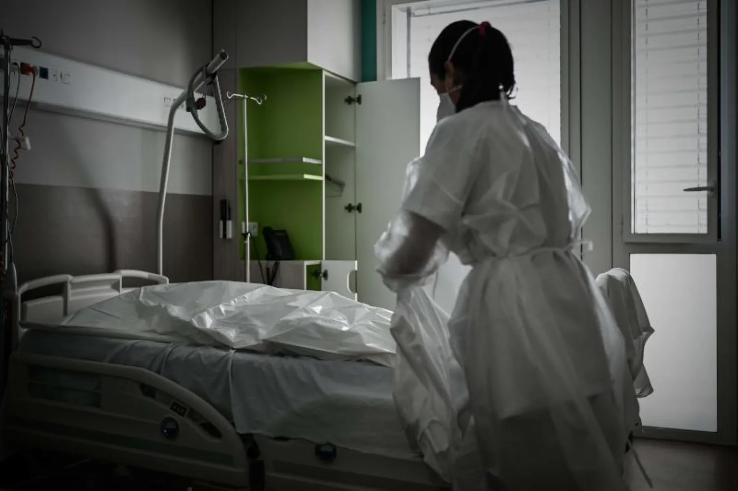 عاملة بالقطاع الطبي تغطي جثة أحد ضحايا «كوفيد-19» في مستشفى بجنوب غرب فرنسا (أ.ف.ب)