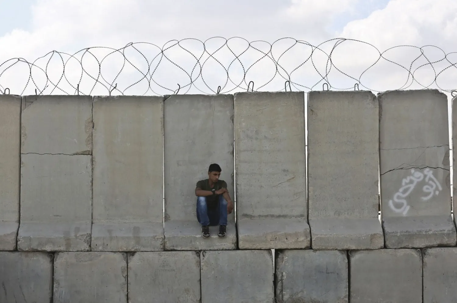 A man sits on cement barricades at the Kerem Shalom crossing in Rafah. (AFP)