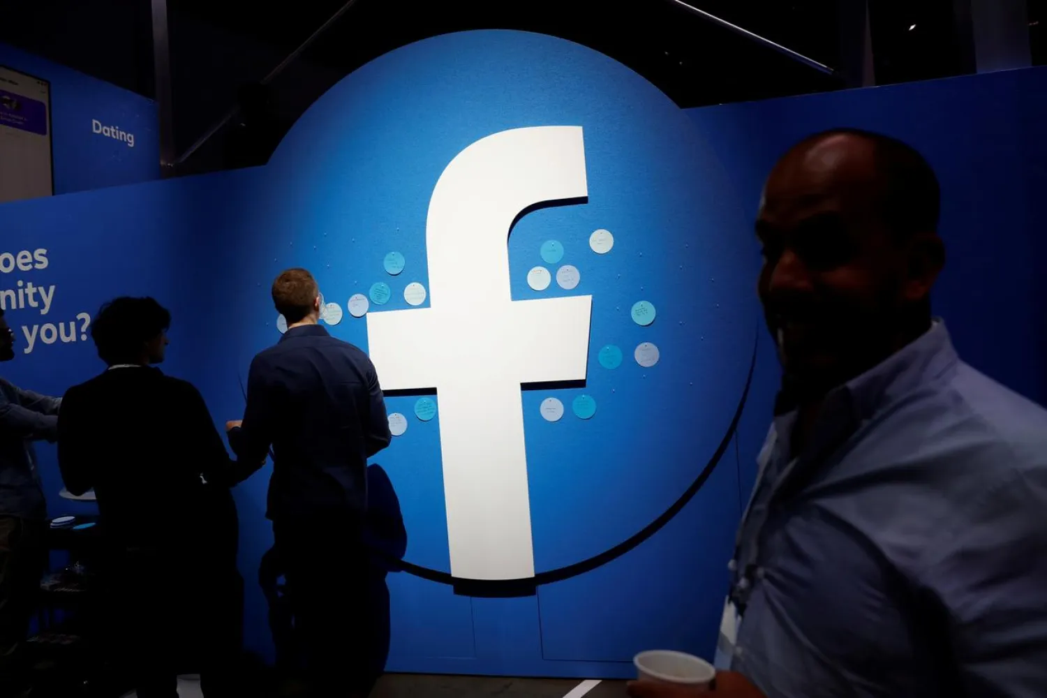 FILE PHOTO: Attendees walk past a Facebook logo during Facebook Inc's F8 developers conference in San Jose, California, United States, April 30, 2019. REUTERS/Stephen Lam/File Photo