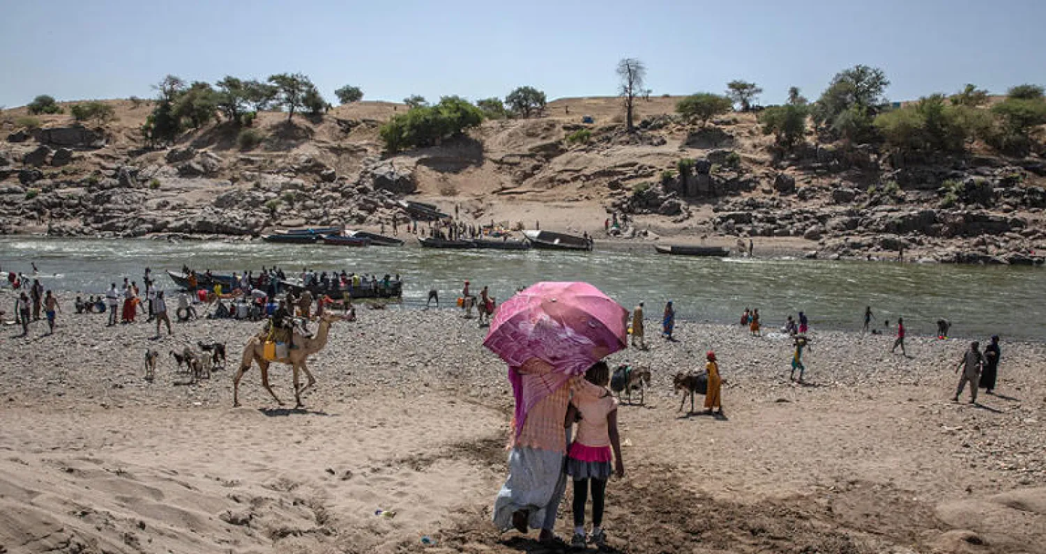 نازحون من تيغراي يعبرون نهراً للوصول إلى شرق السودان (أ.ب)
