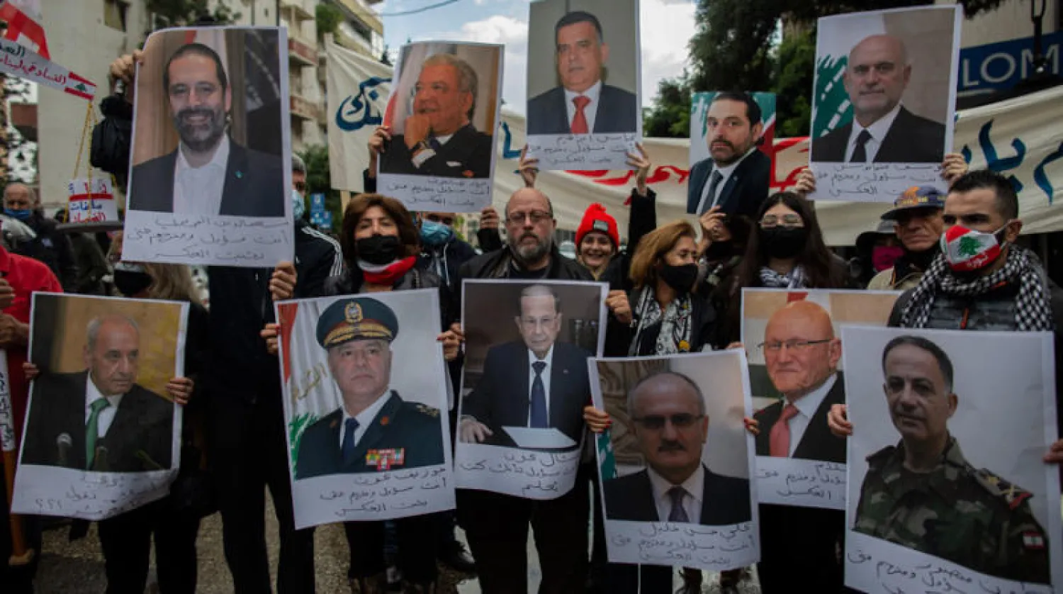 متظاهرون يحملون في بيروت أمس صور زعماء لبنانيين يتهمونهم بالمسؤولية عن انفجار المرفأ (أ.ب)