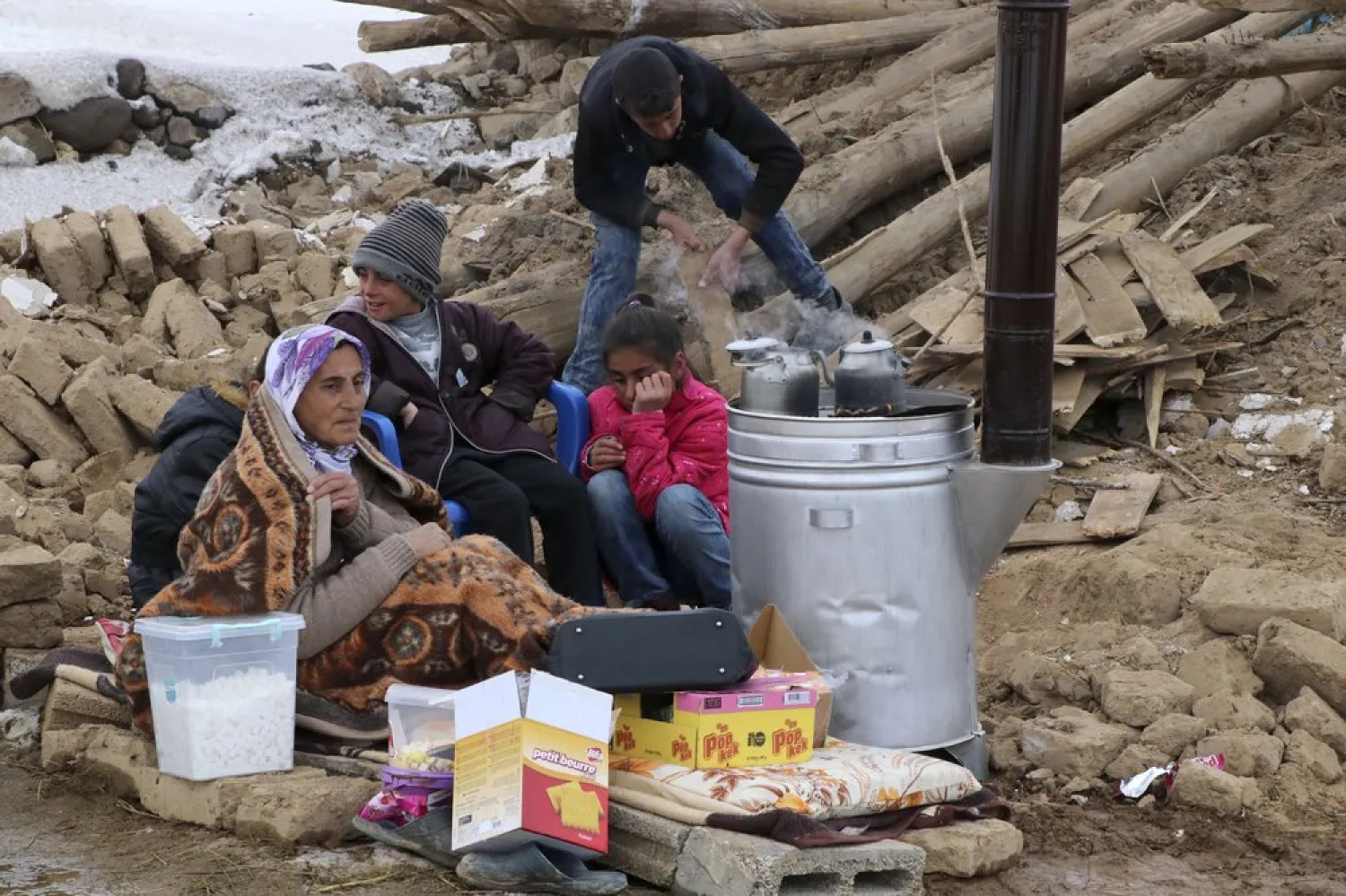 FILE: People try to warm up around a stove outside their collapsed house after an earthquake hit villages in Baskale town in Van province, Turkey, at the border with Iran, Sunday, Feb. 23, 2020. AP