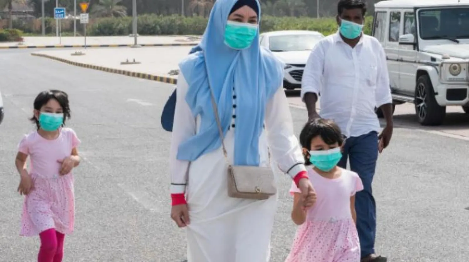 عائلة مقيمة يرتدون كمامات عند وصولهم إلى مركز اختبار الفيروس بمدينة الكويت (رويترز)