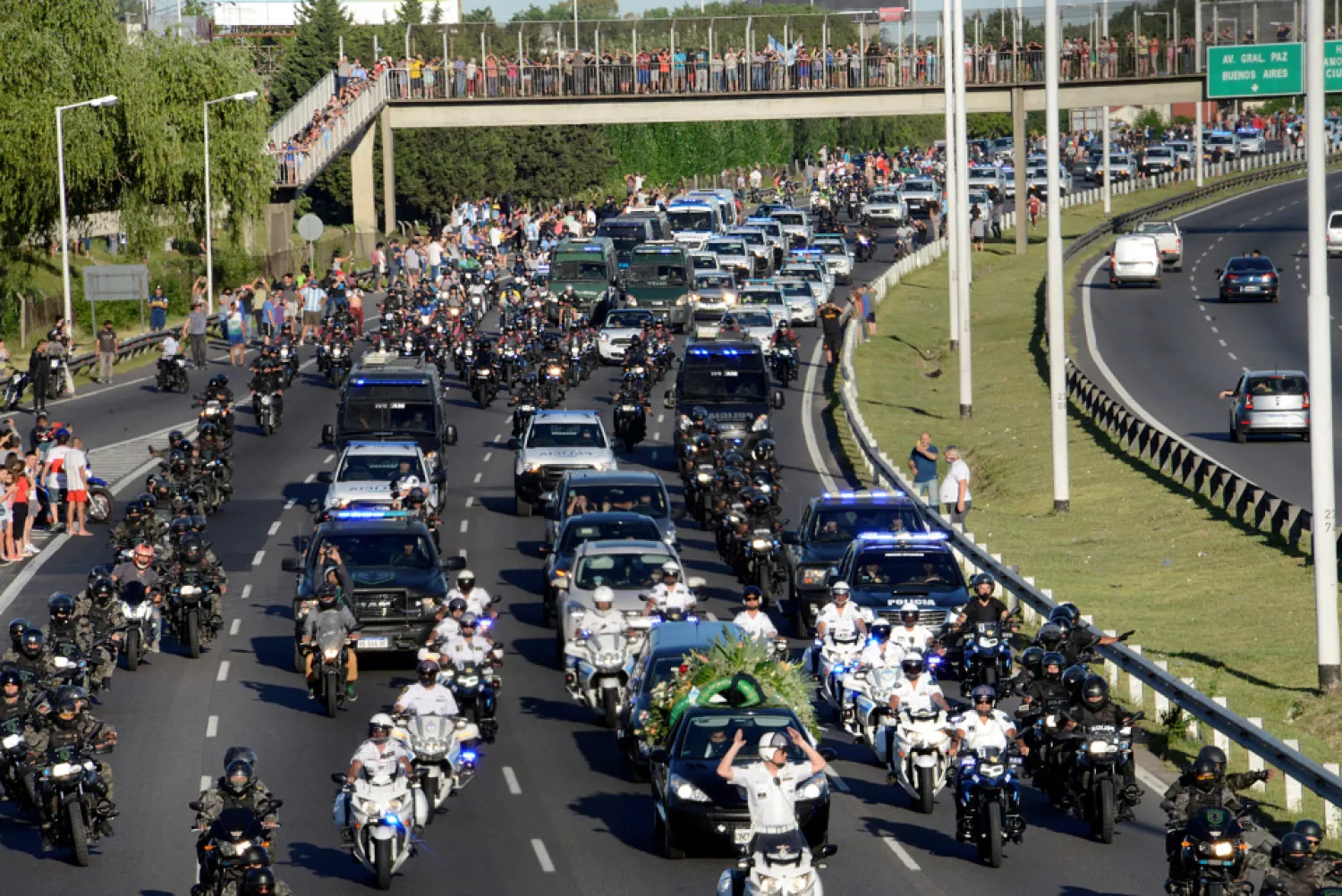 People stand on the bridge and the highway as a large number of security vehicles escort the football player's hearse on the 25 de Mayo Highway. Reuters