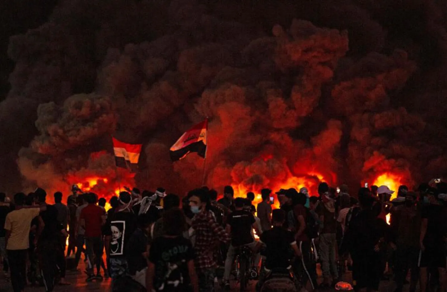 متظاهرون عراقيون يتجمعون قرب إطارات محترقة خلال احتجاج في مدينة البصرة (أ.ف.ب)