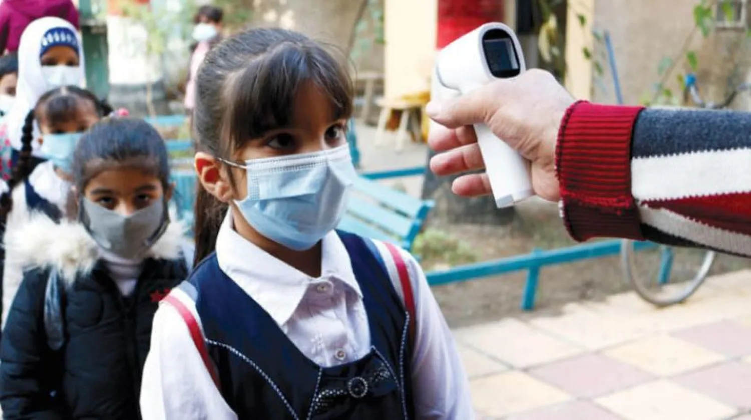 Dün Bağdat’ta sınıflara girilmeden önce ateş ölçümü yapıldığı esnada. (Reuters)