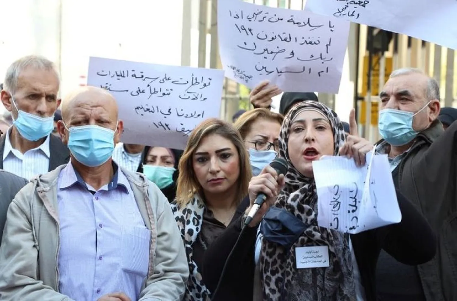 People hold placards during a protest by parents of students studying abroad in front of Lebanon's central bank in Beirut, Lebanon November 18, 2020. (Reuters)