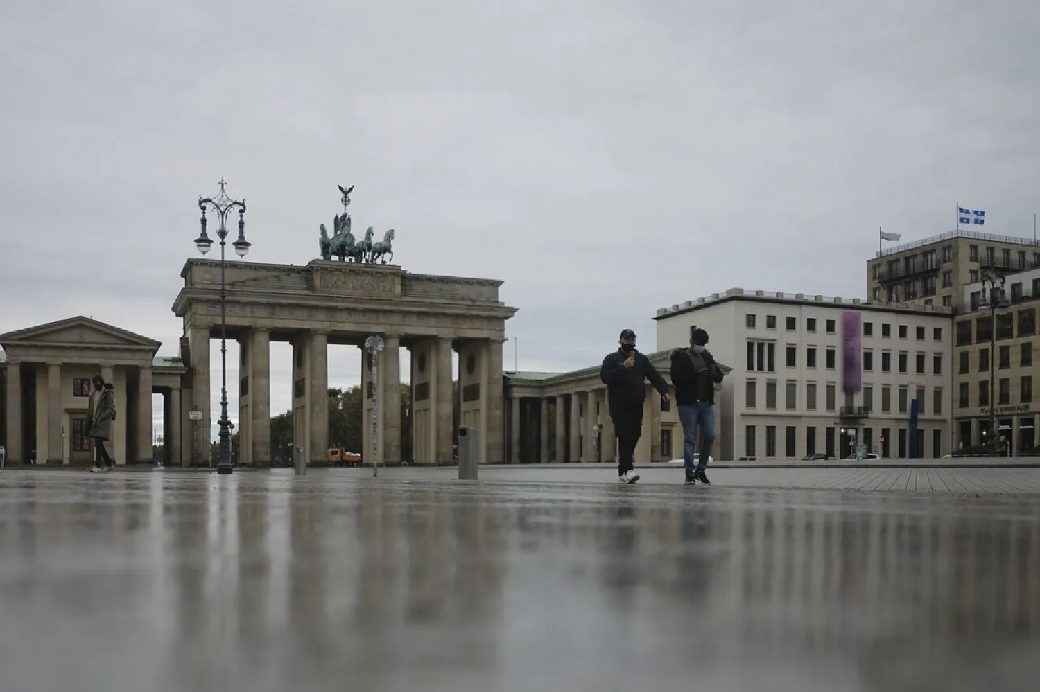 Two man wearing face masks cross the deserted Pariser Platz in front of the Brandenburg Gate, a tourist highlight, in Berlin, Germany, Monday, Nov. 2, 2020. (AP)