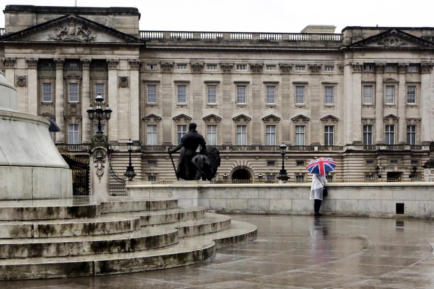 FILE PHOTO: A tourist stands in the rain outside Buckingham Palace in London, Britain August 31, 2015. REUTERS/Kevin Coombs