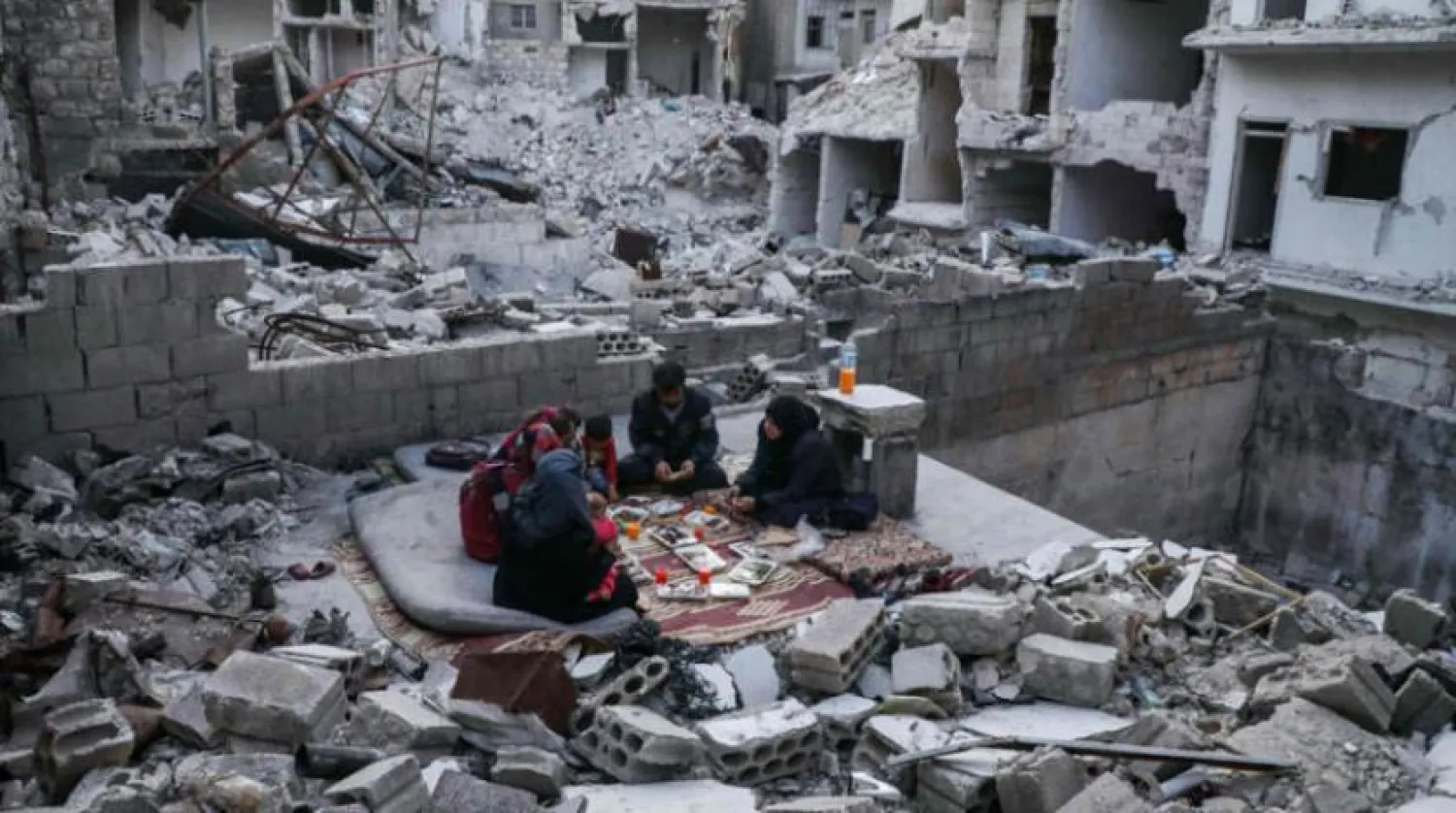 İdlib kırsalındaki enkazda yemek yiyen bir aile. (AFP)