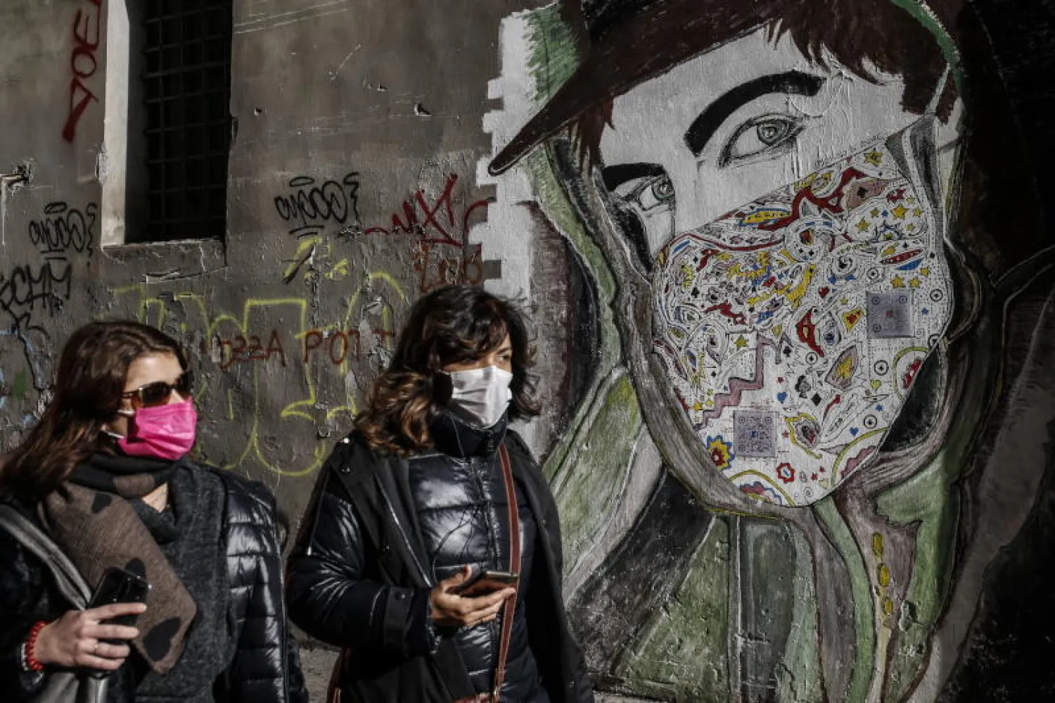 سيدتان تضعان كمامتين للحماية من كورونا أثناء تجولهما في أحد شوارع روما (إ.ب.أ)