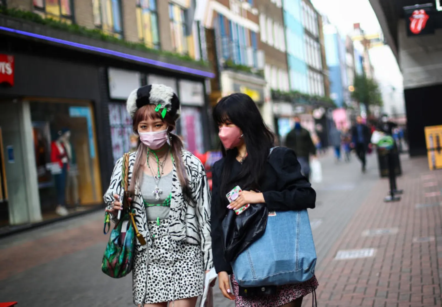 سيدتان تضعان كمامتين في شارع أكسفورد التجاري بلندن (رويترز)