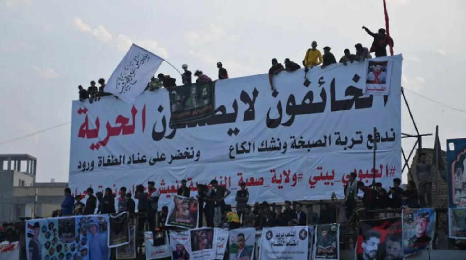 Iraqi demonstrators gather beneath a banner which reads "the fearful cannot bring about freedom" in Habboubi square, in the southern city of Nasiriyah in Dhi Qar province, on December 4, 2020, to express anger after followers of cleric Moqtada Sadr clashed with young protesters lately. (Photo by Asaad NIAZI / AFP)