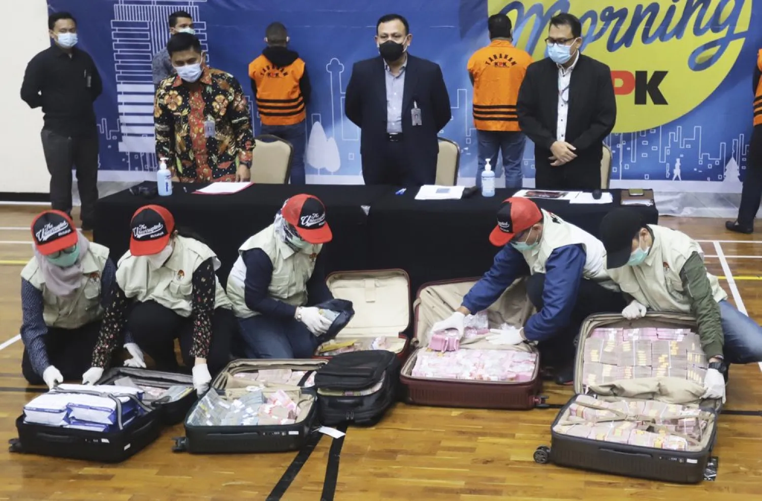 Officers arrange suitcases full of rupiah and U.S. dollar bills confiscated from suspects as Chairman of Indonesia's Corruption Eradication Commission Firli Bahuri, top center, looks on during a news conference on a corruption case involving government's COVID-19 pandemic aid distribution, in Jakarta, Indonesia, Sunday, Dec. 6, 2020 - (AP Photo/Birendra)
