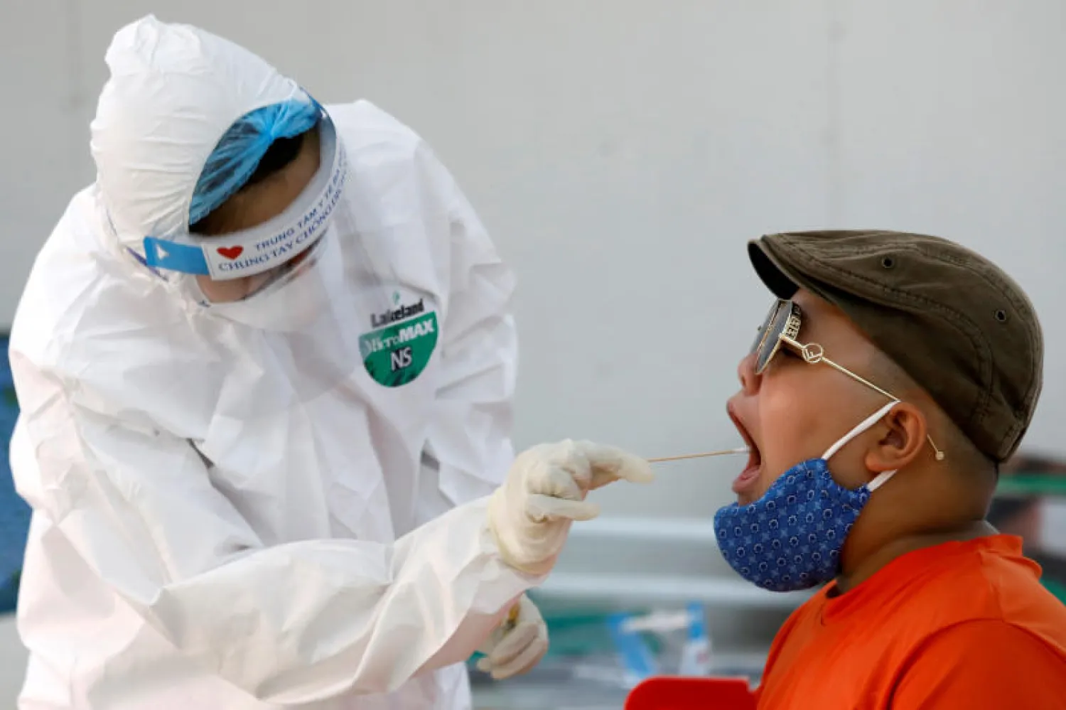 طبيب يرتدي بدلة واقية يجري مسحة لمسافر عاد من دا نانغ في مركز اختبار سريع في هانوي (رويترز)
