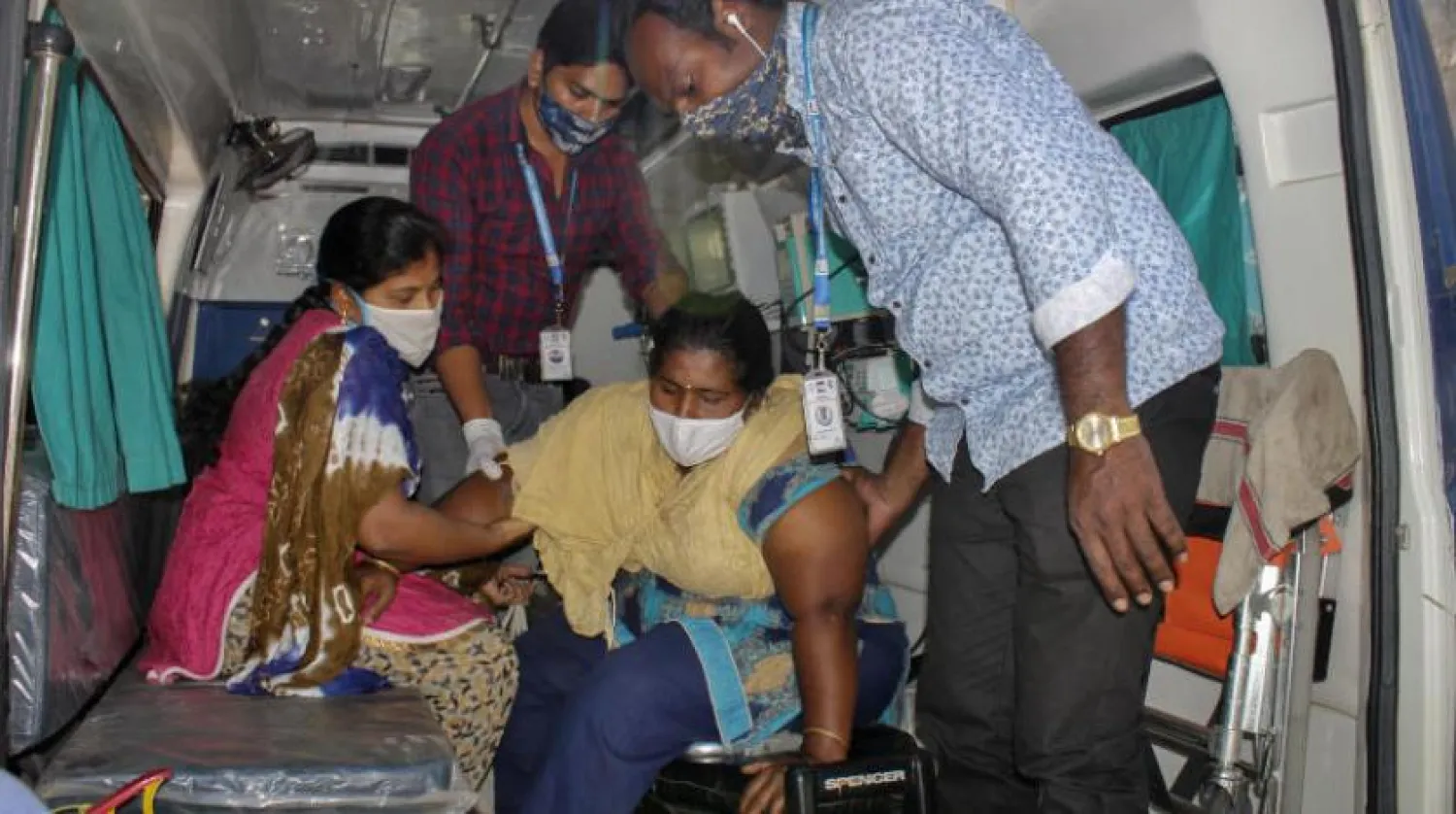 Hindistan’ın Andra Pradeş eyaletinde ortaya çıkan gizemli hastalıktan şikayetçi kadın ambulanstan inerken yardım alıyor. (AP)