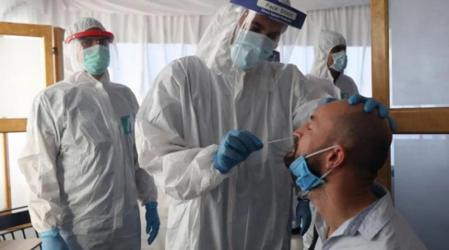 عامل صحي يجمع عينات للاختبار عند وصول السائحين إلى مركز الفحص في مطار شرم الشيخ الدولي (أرشيفية-إ.ب.أ)