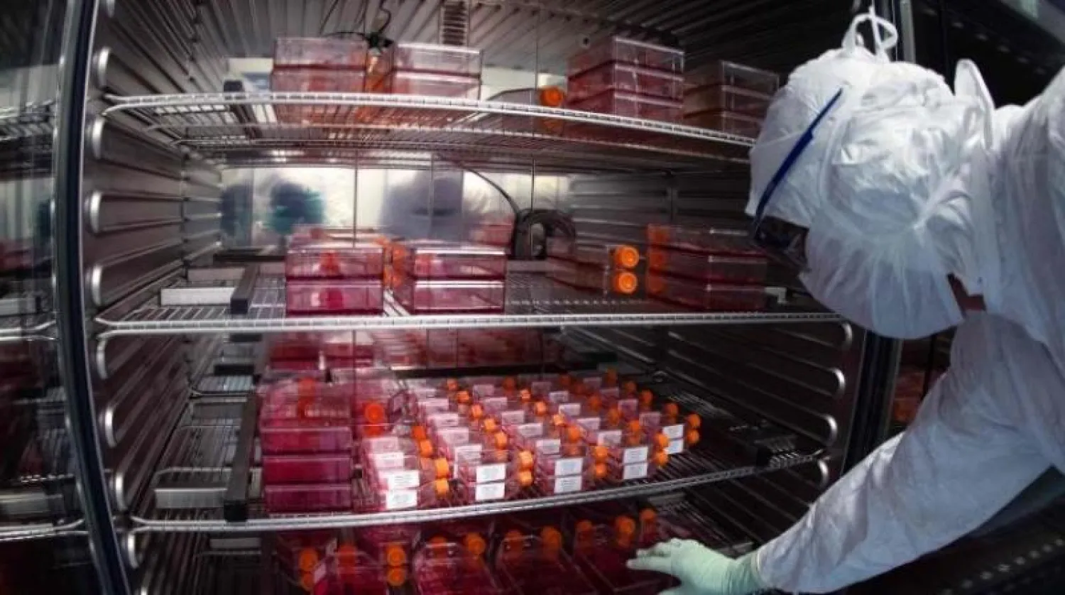 فني مختبر يرتدي معدات الحماية الشخصية وهو يأخذ زجاجات الكاشف لإجراء اختبارات اللقاح في مختبر «سانوفي» (أ.ف.ب)