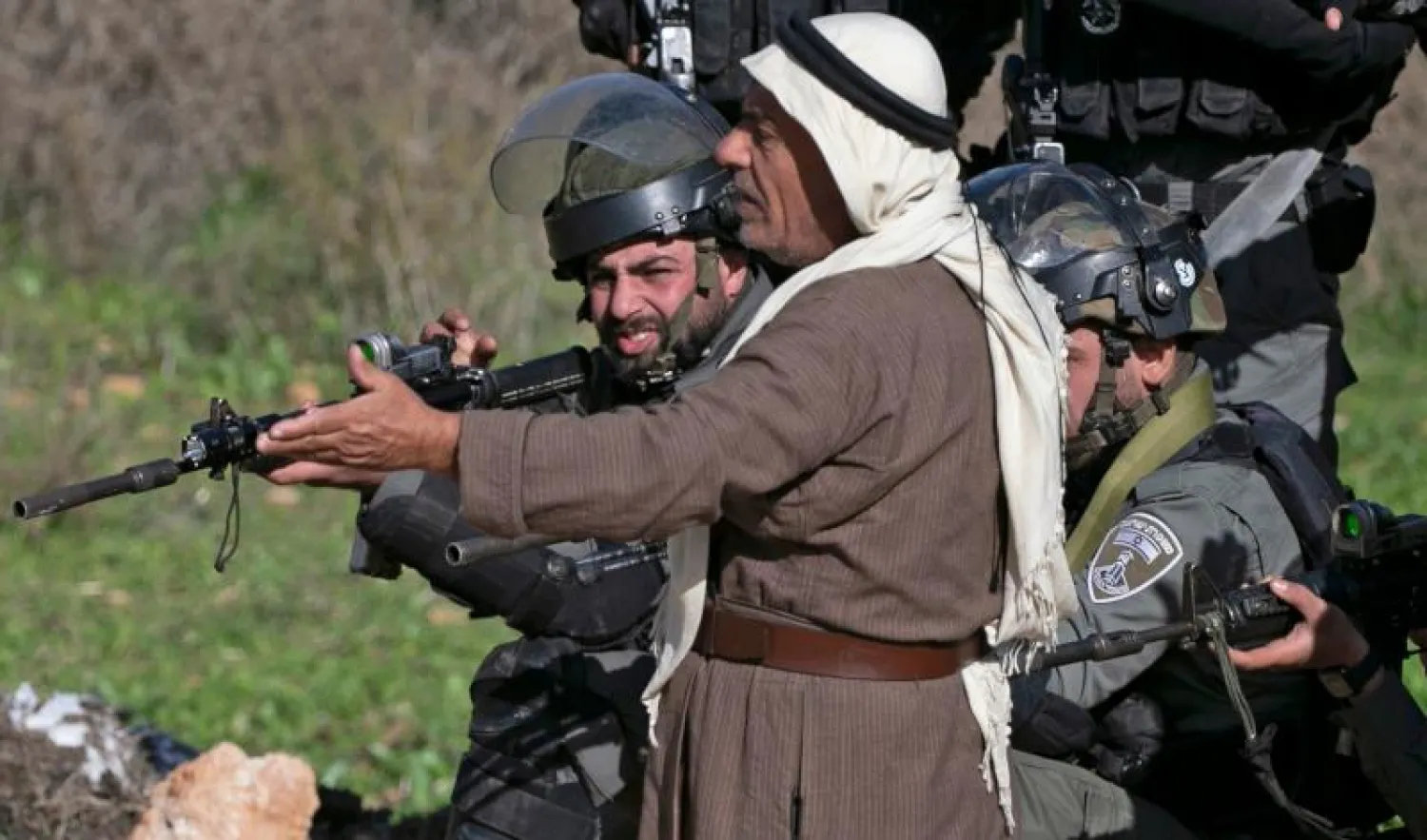 مسن فلسطيني يقف أمام القوات الإسرائيلية خلال مظاهرة للاحتجاج على توسيع المستوطنات في الضفة الغربية (أ.ف.ب)